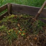 Kompostownik ogrodowy z mieszanką odpadów organicznych i widłami do napowietrzania kompostu
